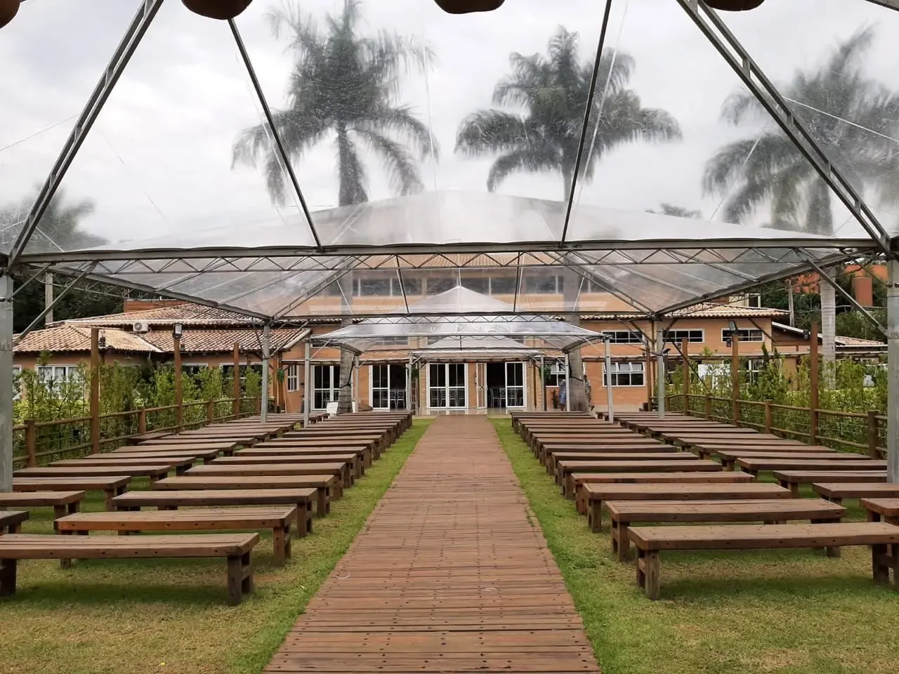 Tenda transparente decorada com corredor de madeira para cerimônia de casamento