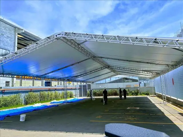 Sequência de tendas piramidais brancas montadas lado a lado para evento de grande porte